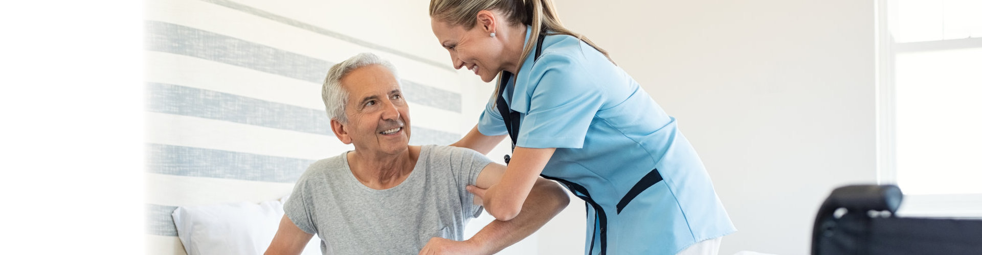 young nurse helping the old man to get up from the bed